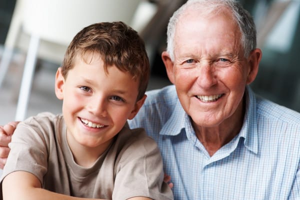 A smiling grandfather and grandson posing for a photo