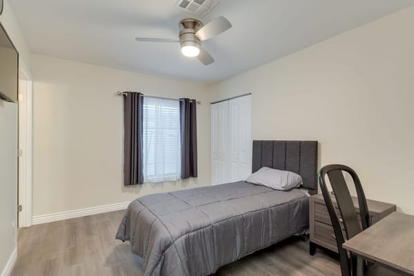 A simple interior view of a resident's room with a bed and desk