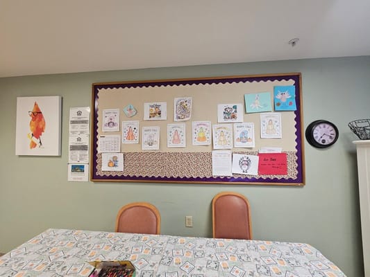 A bulletin board with colorful artwork in a common area