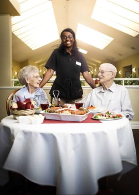 Resident dining with staff service in an inviting dining room