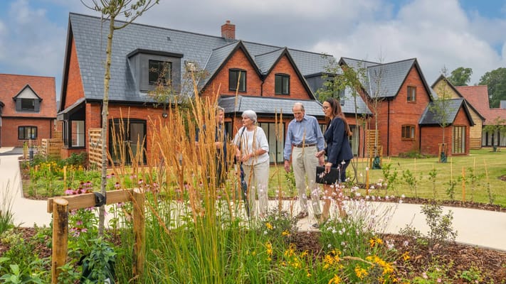 Residents and staff walking in the garden outside the facility