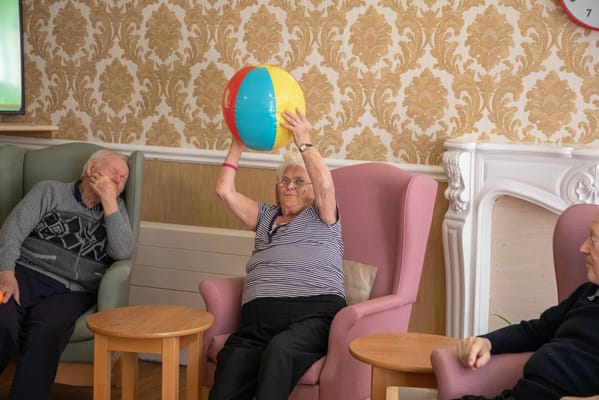 Residents engaging in a lively indoor activity with a beach ball