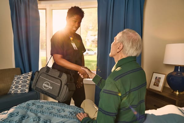 A caregiver shaking hands with a senior resident indoors