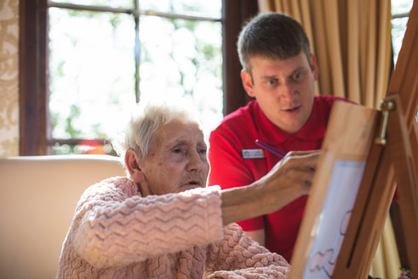 Resident engaging in art activity with staff member