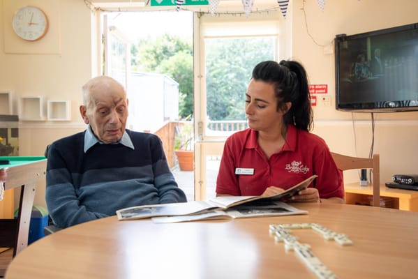 Senior resident and staff member reading together