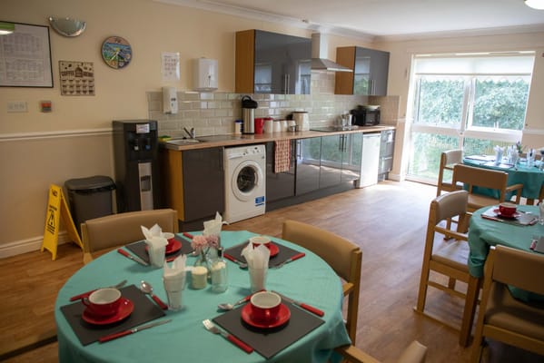 Interior view of a dining area with tables and a kitchenette