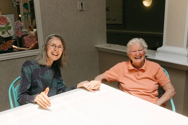 Two smiling residents sitting at a table indoors