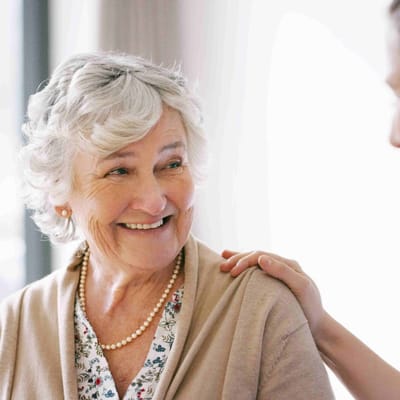 A smiling elderly woman interacting with staff