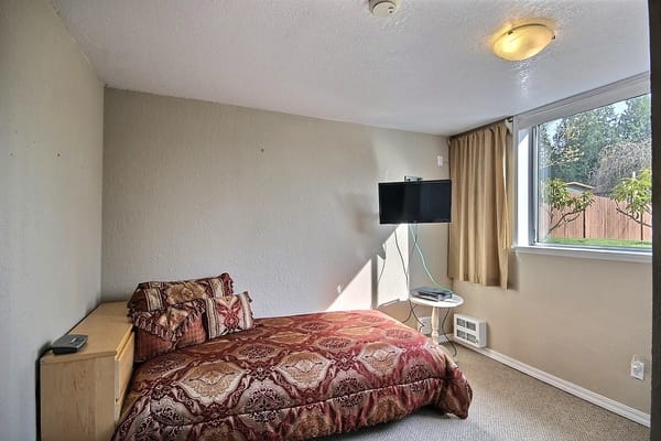 Brightly lit private room with a bed and TV