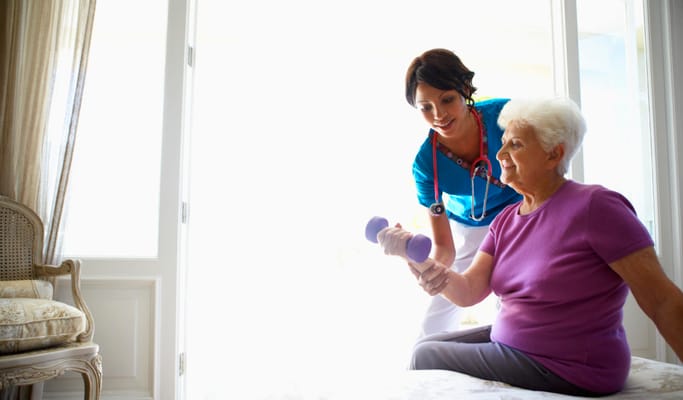 Staff assisting a resident with weights in an interior setting