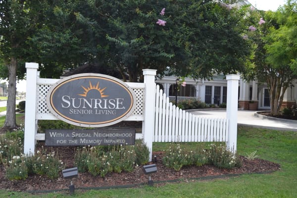 Entrance sign of Sunrise Senior Living with a decorative fence