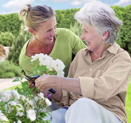 A caregiver and resident gardening together in a sunny outdoor space