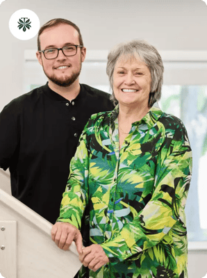A resident and staff member smiling indoors