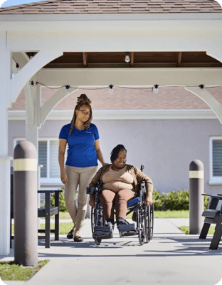 Staff assisting a resident in a wheelchair outdoors