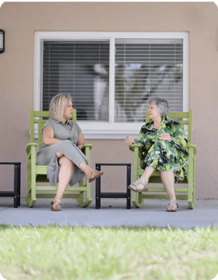 Two women chatting outside on rocking chairs