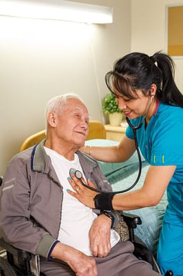 A nurse checking a resident's heartbeat in care