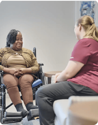 A resident in a wheelchair conversing with a staff member