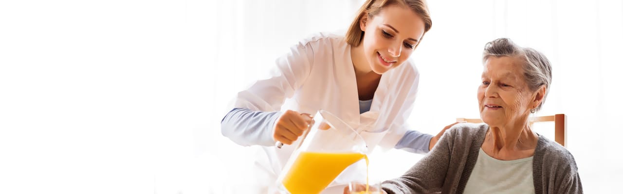 Caregiver pouring juice for a senior resident