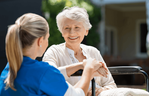 Caregiver conversing with a smiling resident outdoors