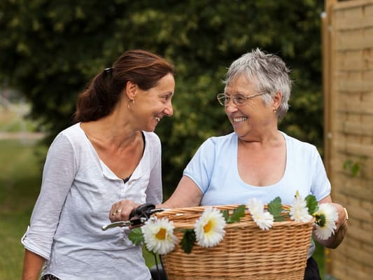Two women smiling outdoors with a decorated basket