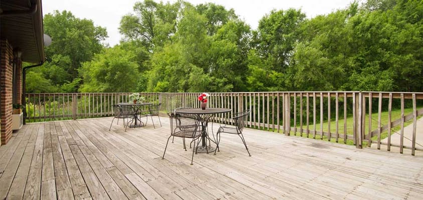 Outdoor deck area with tables and chairs surrounded by trees