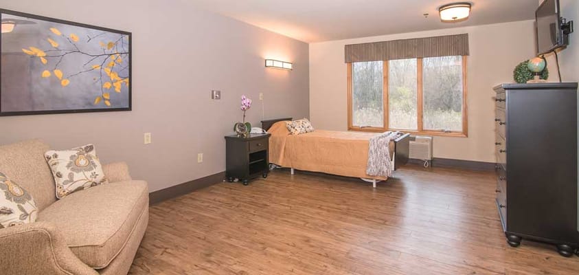 Interior view of a private resident room with a bed and sofa