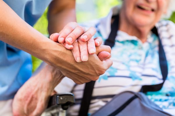 Close-up of caregiver holding hands with a senior resident