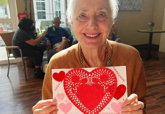 Resident proudly holds up a Valentine’s Day craft