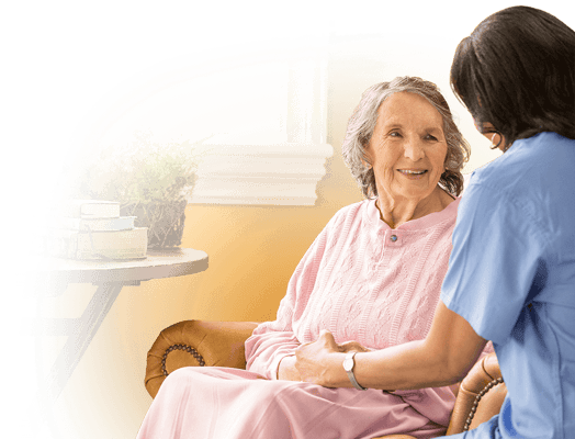 A caregiver interacting with a smiling resident in a sunny room