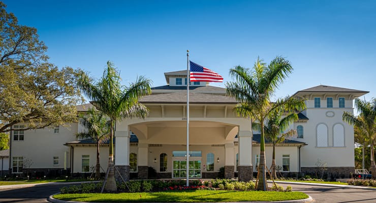 Exterior view of a senior living facility with palm trees