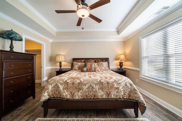 A cozy bedroom with a patterned bedspread and ceiling fan