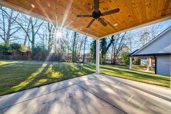 Covered outdoor patio with sunlight shining through trees