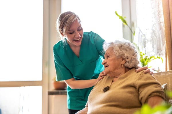 Caregiver smiling with an elderly resident in a cozy room
