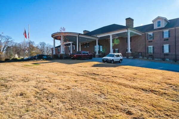 Exterior view of a senior living facility with vehicles