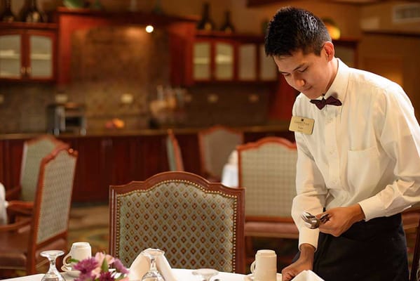 Staff member setting a dining table in the dining room
