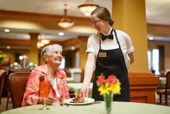 Resident enjoying a meal with a staff member in the dining room