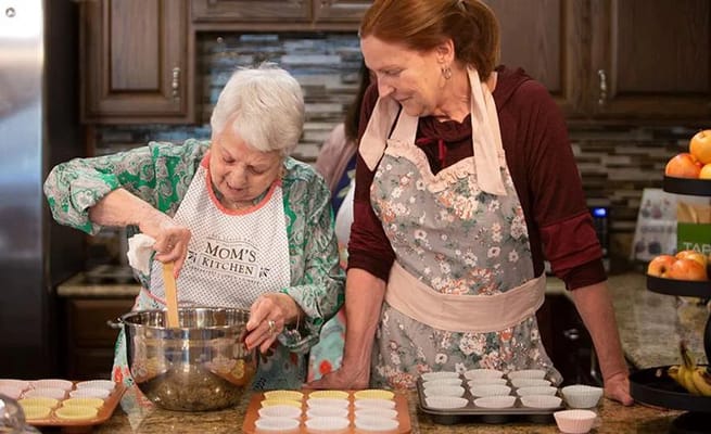 Two women mixing ingredients in a bowl while baking in the kitchen.
