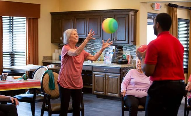 Resident participating in a ball game activity with staff and other residents