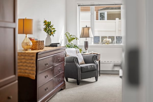 A cozy resident room with a chair and dresser