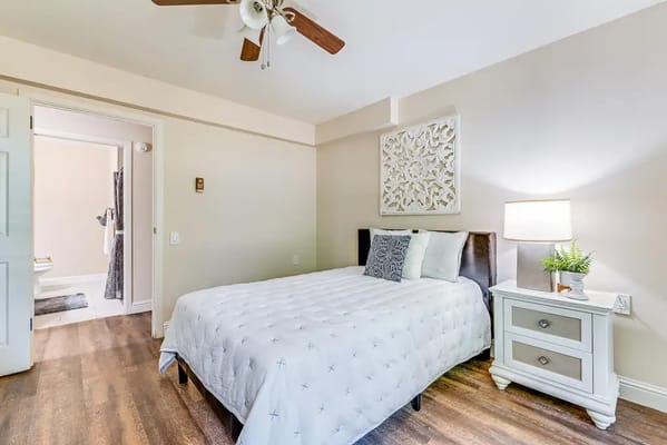 Well-decorated private resident room with a bed and lamp