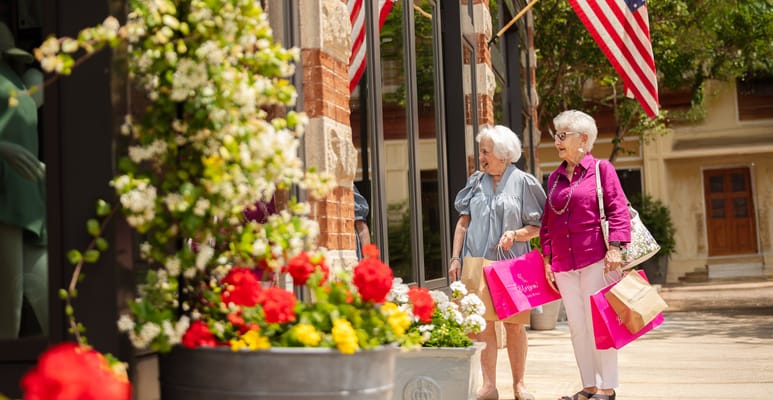 Two seniors shopping outside a boutique with flowers and flags