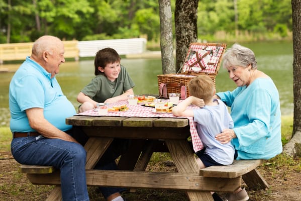 Elderly couple enjoying a picnic with children by a lake