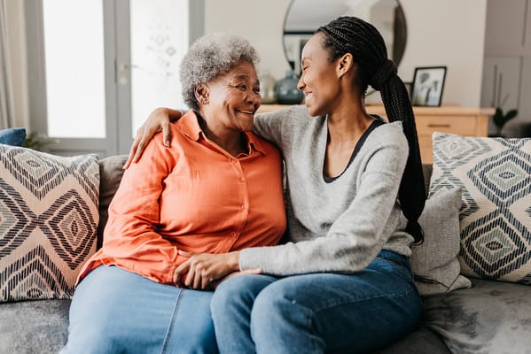 Two women smiling and enjoying a moment together on a couch