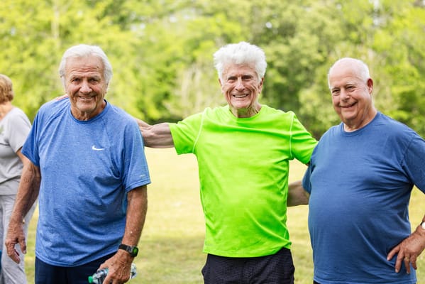 Three smiling seniors in a green park