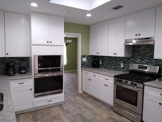 Modern kitchen interior with white cabinets and green backsplash