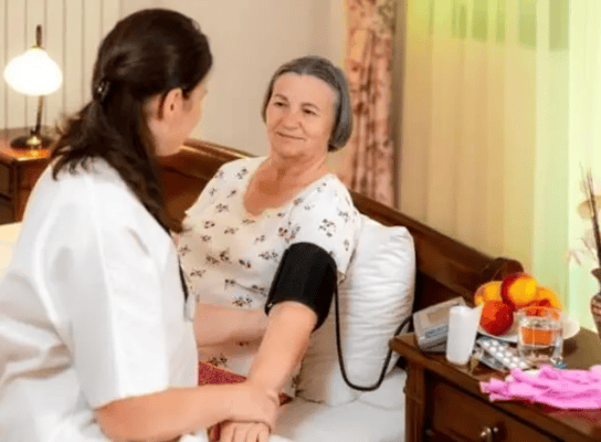 A caregiver taking a resident's blood pressure in a room