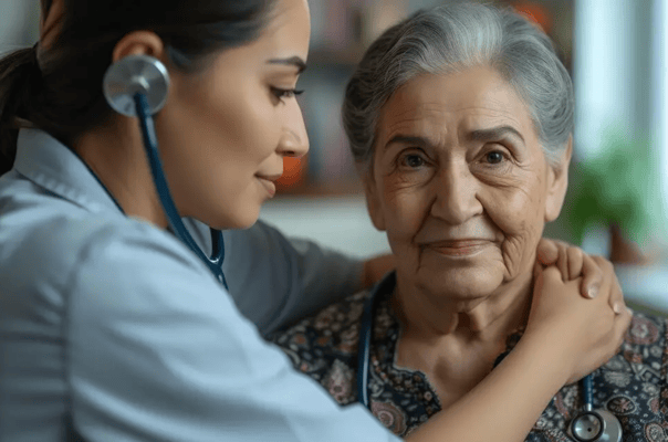 A caregiver with a stethoscope embracing an elderly woman