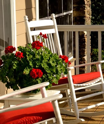 Rocking chairs on a porch with red flowers