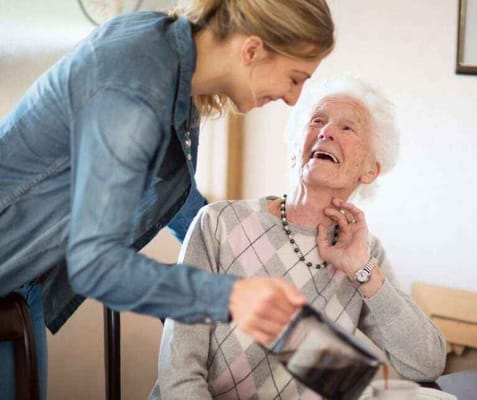 A caregiver laughing with a resident at a table