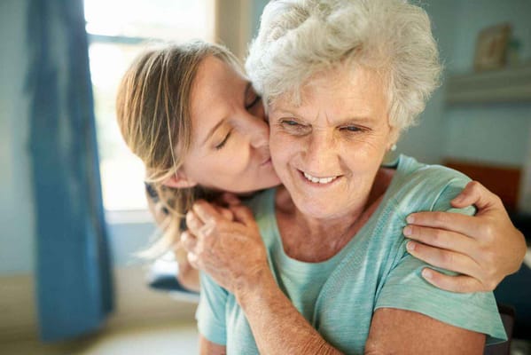 A caregiver and a resident smiling together